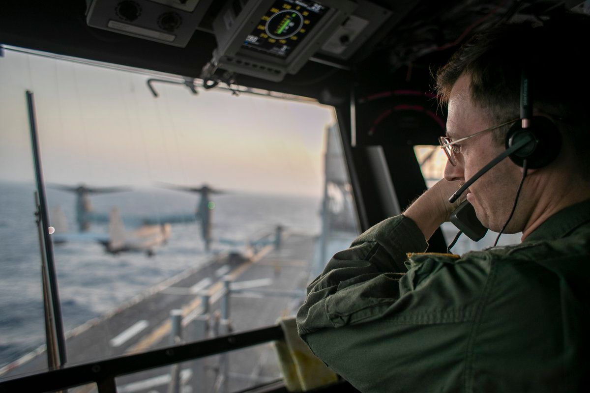 @U.S. Central Command: A naval officer aboard USS Tripoli (LHA 7) oversees flight operations from the control tower as the amphibious assault ship sails in the Arabian Sea. U.S. warships and aircraft deployed to the Middle