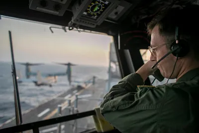 @U.S. Central Command: A naval officer aboard USS Tripoli (LHA 7) oversees flight operations from the control tower as the amphibious assault ship sails in the Arabian Sea. U.S. warships and aircraft deployed to the Middle 