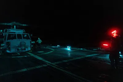 @U.S. Central Command: A U.S. Sailor directs an MH-60R Sea Hawk helicopter during nighttime flight operations aboard guided-missile cruiser USS Princeton (CG 59) as the ship sails in the Arabian Sea and enforces the U.S. bl